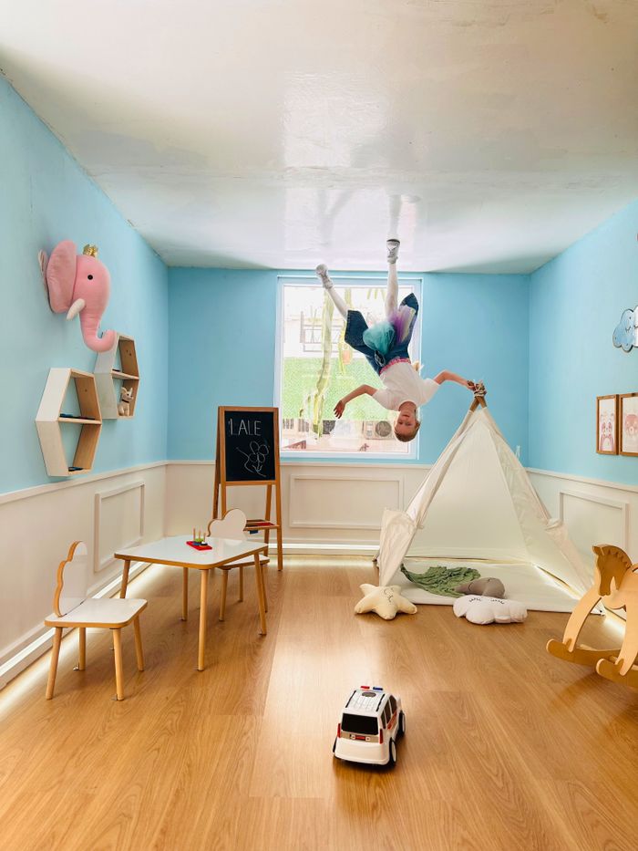 A surreal scene of a child in a playful blue playroom with upside-down furniture and decor, creating a whimsical atmosphere.